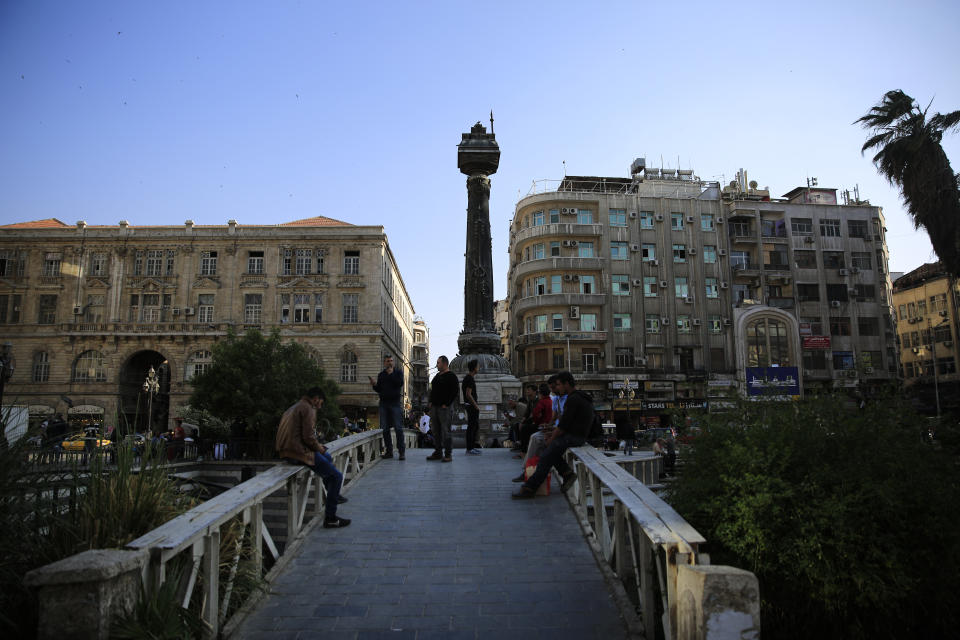 FILE - In this April 15, 2018 file photo Syrians gather in the Marjeh square in Damascus, Syria. A new Syrian law empowering the government to confiscate property is threatening to leave refugees stuck in Europe with no homes to return to. (AP Photo/Hassan Ammar, file)