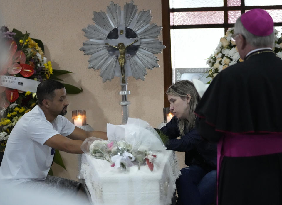 Los padres de la niña Larissa Maia Toldo, de siete años, quien fue asesinada por un hombre con un hacha dentro de una guardería, se sientan junto al ataúd que contiene sus restos durante un velorio en el cementerio de São José, en Blumenau, Brasil, el jueves 6 de abril de 2023. (AP Foto/André Penner)