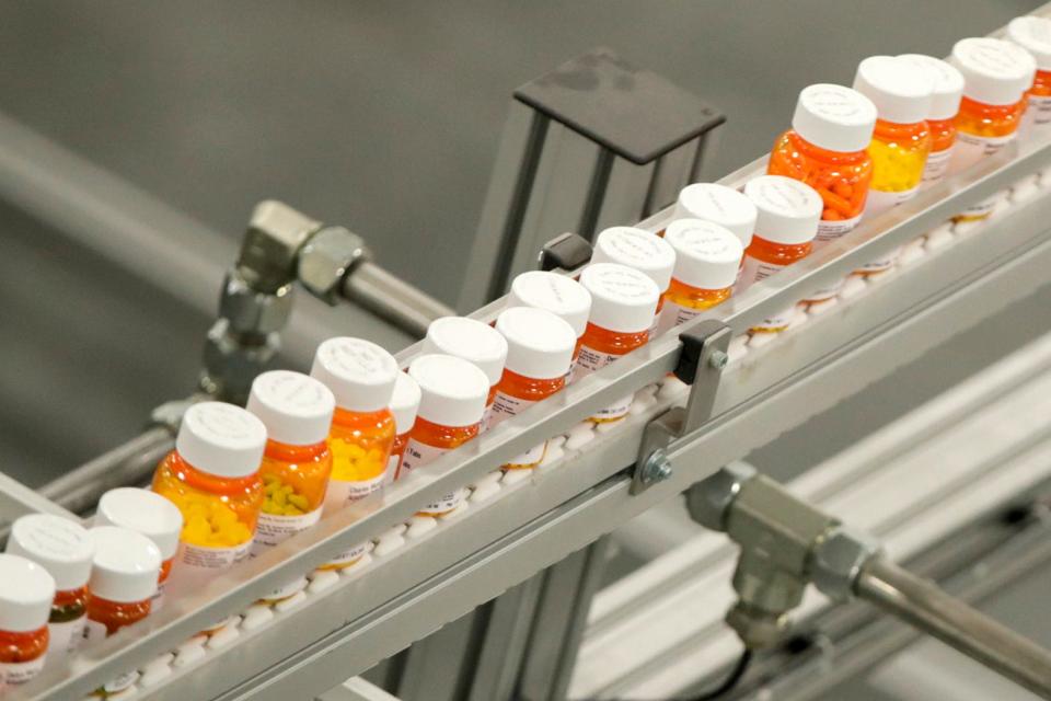 FILE- Bottles of medicine ride on a belt at a mail-in pharmacy warehouse. (AP Photo/Julio Cortez, File)