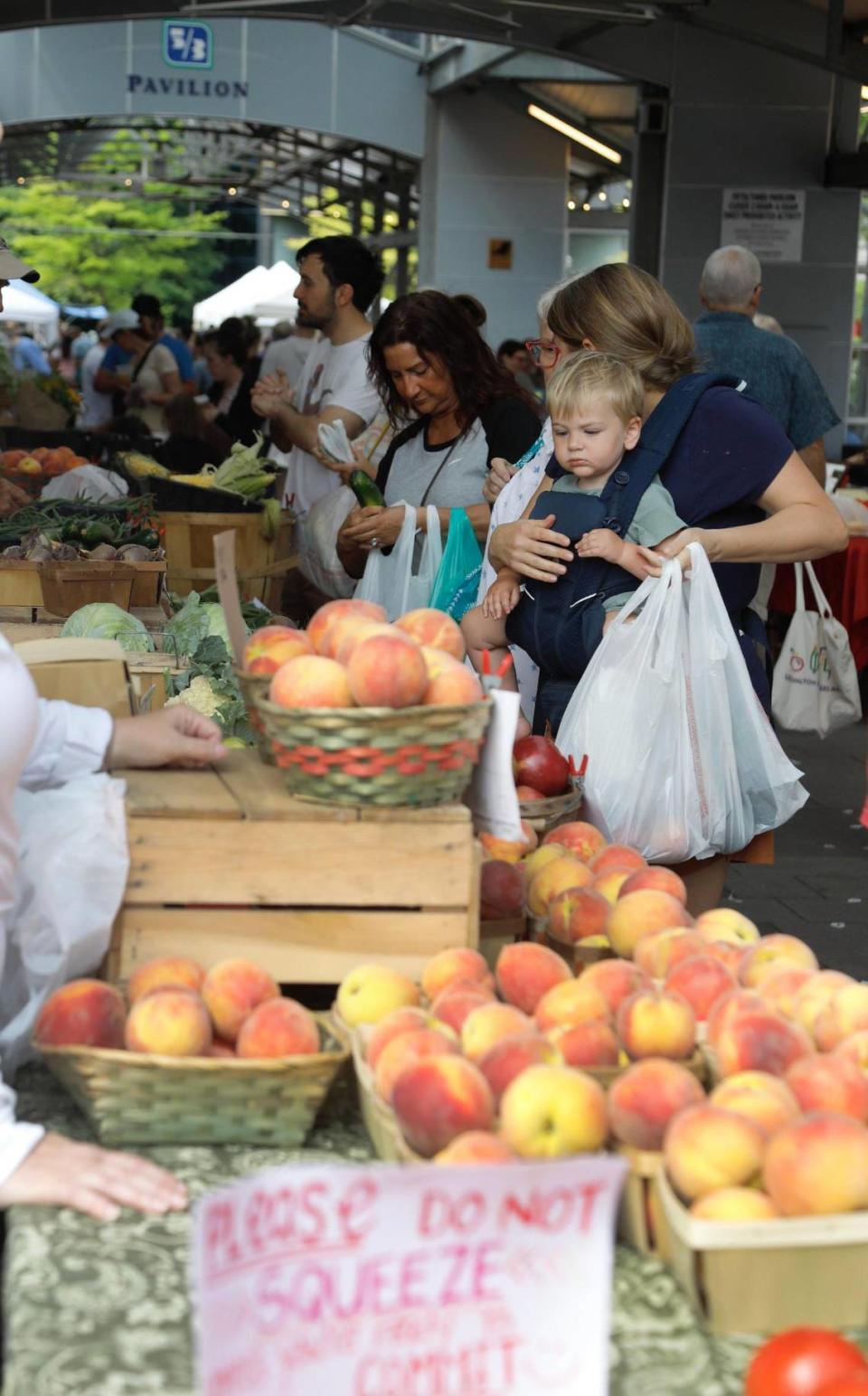 Customers at the Lexington Farmers Market look over fresh peaches, which are always a big draw.