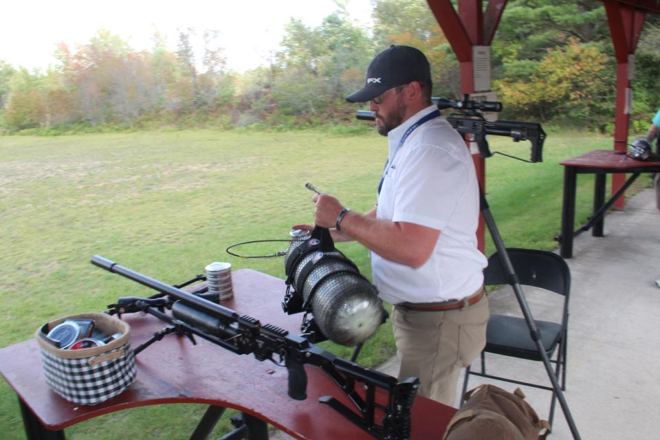 Chris Turek of Traverse City, Michigan, prepares to charge an air rifle with a tank of compressed air during a demonstration at the 2021 Association of Great Lakes Outdoors Writers conference in Gaylord, Michigan.