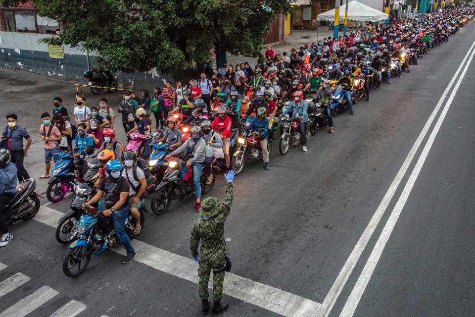 Motorists fall in line at a health checkpoint as authorities begin implementing lockdown measures on March 16, 2020 in San Pedro, Laguna province, on the outskirts of Metro Manila, Philippines. The