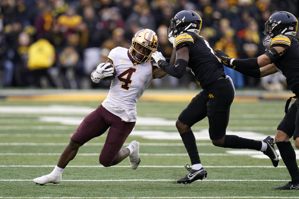 Minnesota running back Mar'Keise Irving (4) runs from Iowa defensive back Matt Hankins, right, during the first half of an NCAA college football game, Saturday, Nov. 13, 2021, in Iowa City, Iowa. (AP Photo/Charlie Neibergall)