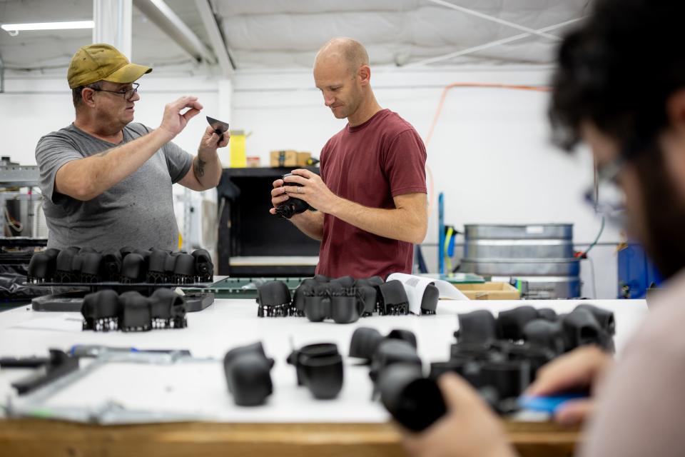 Merit3D CEO Spencer Loveless, center, talks to Jesse Drumm while he does finishing work on 3D-printed parts the company’s manufacturing facility in Price on Thursday, Aug. 17, 2023. | Spenser Heaps, Deseret News