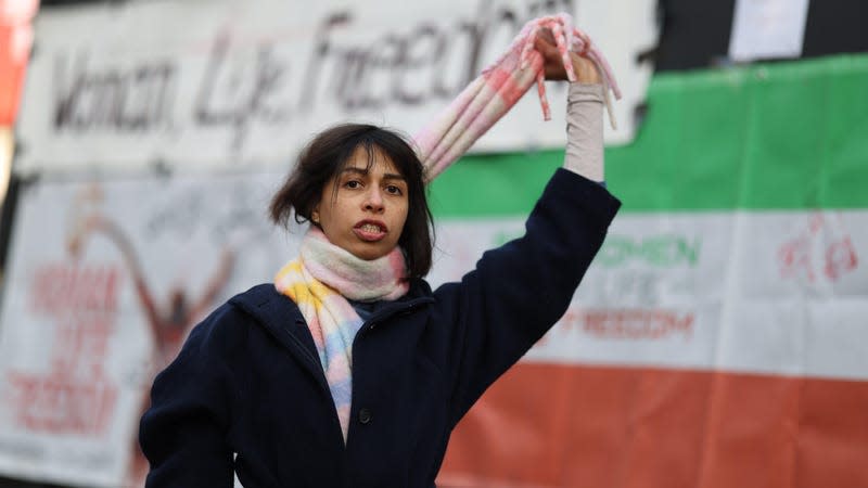 A demonstrator holds a scarf like a noose around her neck during a One Law for All dance protest at Piccadilly Circus on December 17, 2022 in London, England