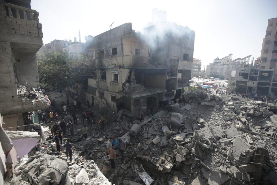 Palestinians look at the aftermath of the Israeli bombing of the Nuseirat refugee camp in Gaza (AP)