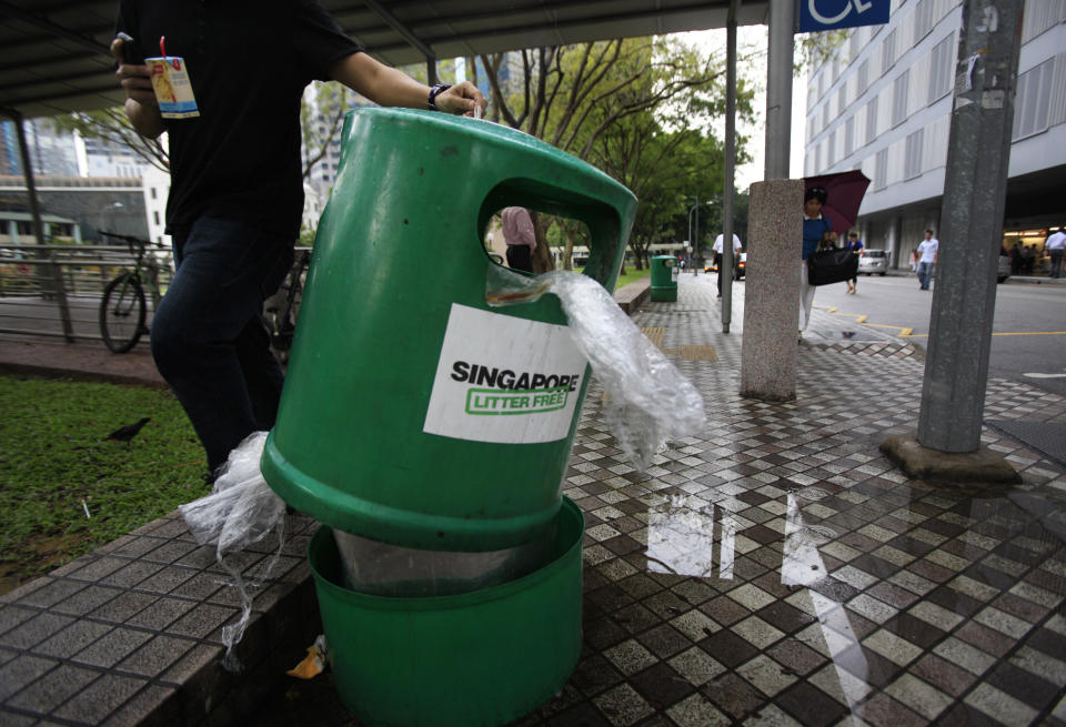 A man stubs out his cigarette on a trash bin bearing "Singapore Litter Free" sticker on Monday, June 7, 2010 in Singapore. Singapore, where painting graffiti can get you caned and drug smugglers are hanged, is trying a new tactic against the city-state's litterbugs: Embarrassing them in front of their neighbors. (AP Photo/Wong Maye-E)