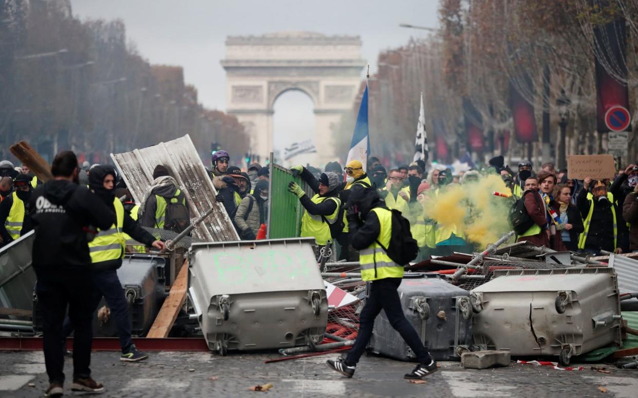 Protesters wearing yellow vests, build a barricade during clashes on the Champs-Elysees in Paris on Saturday November 24 - REUTERS