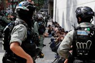 Anti-government demonstrators sit as they were detained during a lunch time protest as a second reading of a controversial national anthem law takes place in Hong Kong