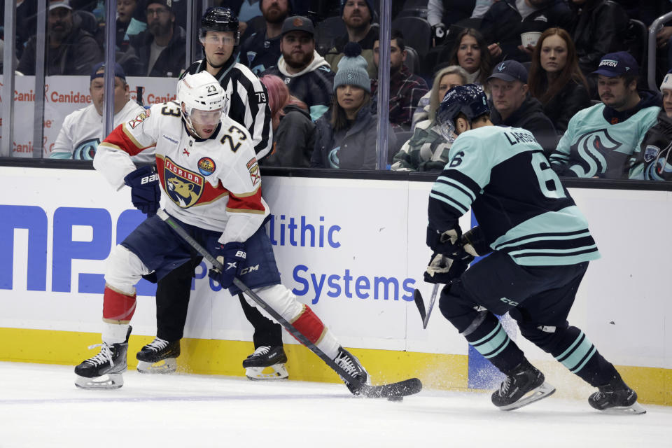 Florida Panthers center Carter Verhaeghe (23) works the puck in front of Seattle Kraken defenseman Adam Larsson (6) during the first period of an NHL hockey game Saturday, Dec. 3, 2022, in Seattle. (AP Photo/John Froschauer)