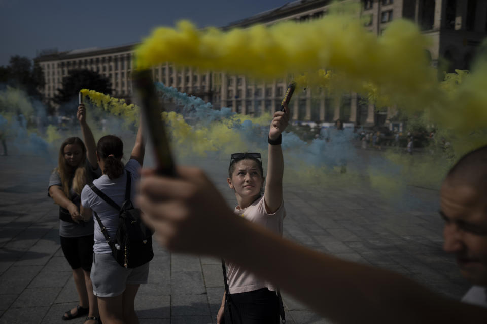 A woman holds a torch at a protest initiated by family members of captured Ukrainian soldiers by Russia in Kyiv, Ukraine, Sunday, Aug. 27, 2023. The protest marks five hundred days since the soldiers were captured in the besieged city of Mariupol. (AP Photo/Bram Janssen)