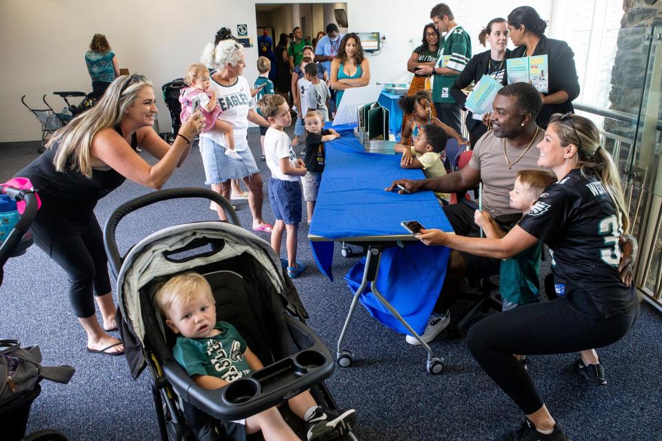 Parent and children take pictures with Brian Westbrook Sr., 42, first-time author and former Philadelphia Eagles running back, after reading from his children's book "The Mouse That Played Football," at the Brandywine Hundred Library in Wilmington, Del., Friday, August 12, 2022. "We try to read a book to leave a message, to leave a legacy with them so they can understand these are the important things in life," said Westbrook to a capacity crowd of family and children.