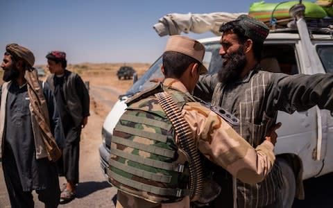 An Afghan police officer searches travelers at a checkpoint on the eastern outskirts of Lashkar Gah city, Helmand, Afghanistan on May 25, 2019. - Credit: Jim Huylebroek for the Telegraph