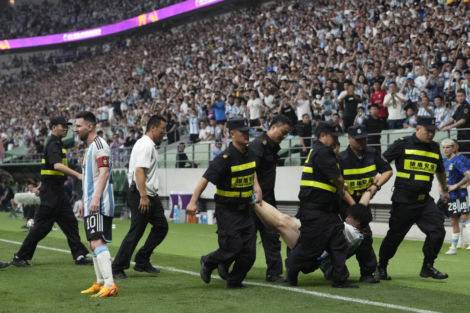 Security guards remove a pitch invader past Argentina's Lionel Messi, left, during the international friendly soccer match between Argentina and Australia at the Workers' Stadium in Beijing, China, Thursday, June 15, 2023. (AP Photo/Andy Wong)
