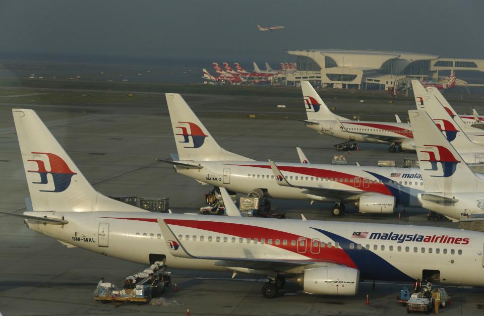 Ground crew work among Malaysia Airlines planes on the runway at Kuala Lumpur International Airport (KLIA) in Sepang