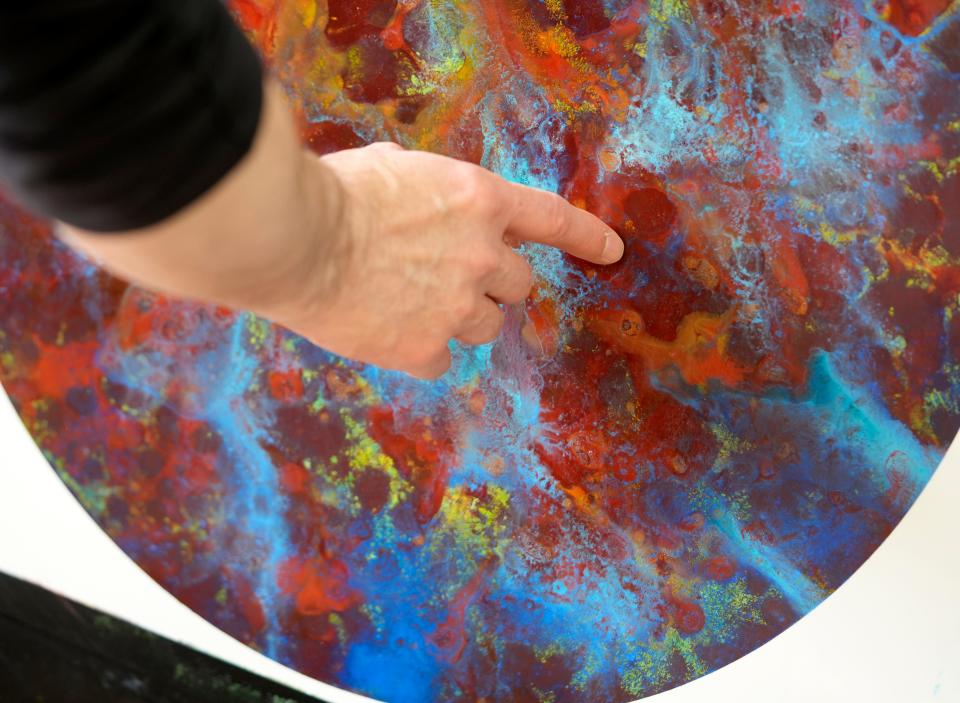 Ohio University art professor John Sabraw shows off art work in his studio on Nov. 10, 2023, that used paint made from the pigment left over after cleaning water from a polluted mine seeps on Truetown Road in Millfield, Athens County.