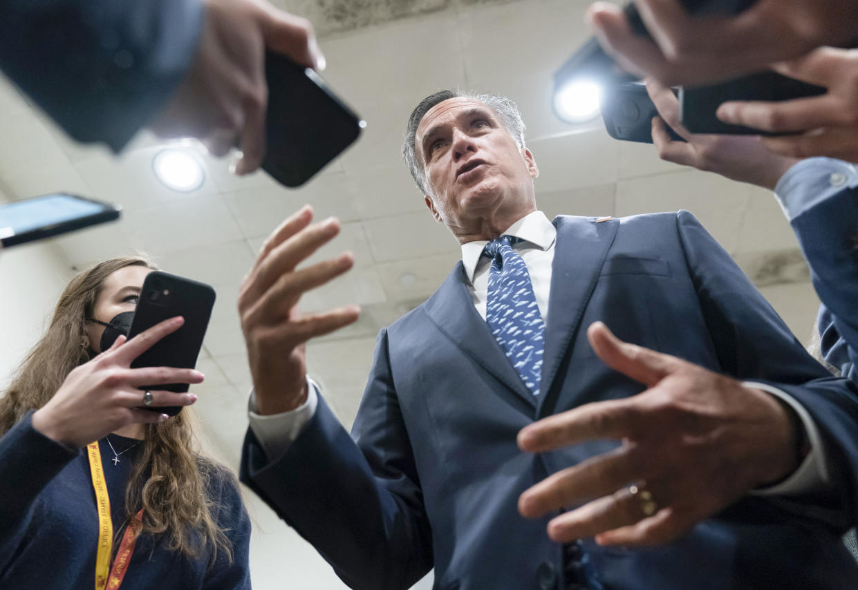 Senator Mitt Romney talks to reporters inside the Capitol.