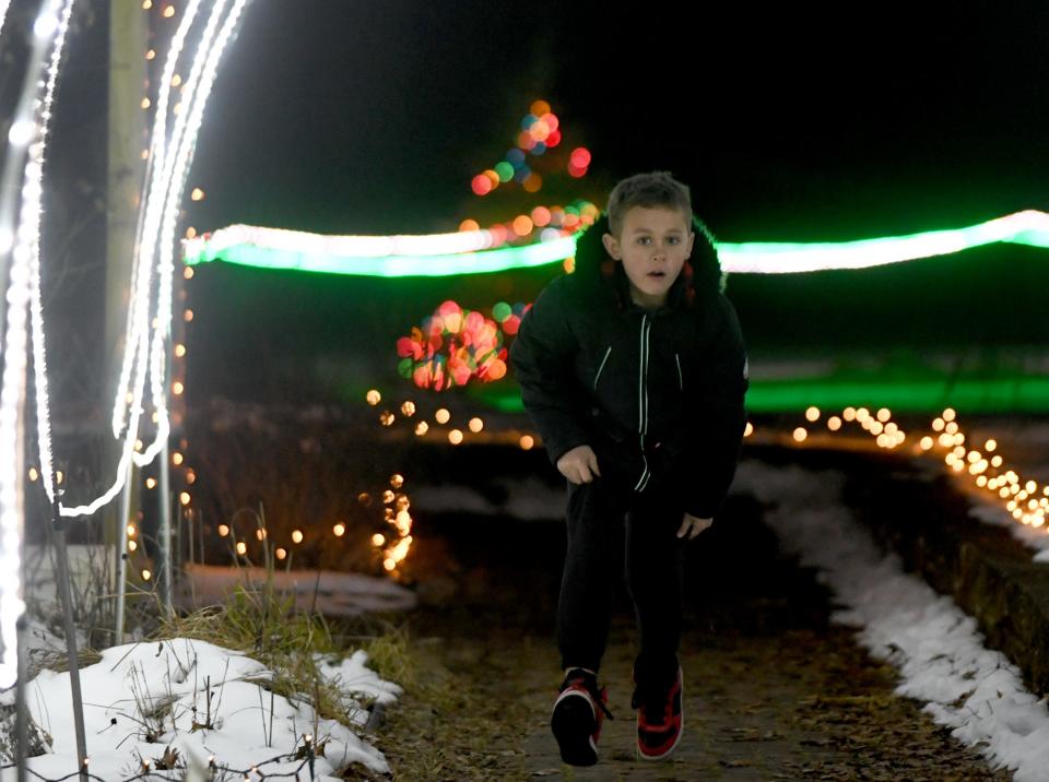 Aiden Schneider, 8, of Massillon runs through the lighted paths at Stark Parks' Deck the Hollow at Quail Hollow Park near Hartville.