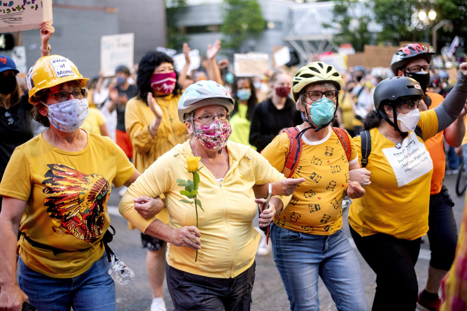 FILE - In this July 20, 2020, file photo, Norma Lewis holds a flower while forming a "wall of moms" during a Black Lives Matter protest in Portland, Ore. More than two months of sustained, intense protests in Portland, Oregon, one of the whitest major cities in America, have captured the world's attention and put a city that's less than 6% Black at the heart of the conversation about police brutality and racism. (AP Photo/Noah Berger, File)