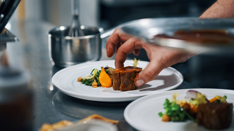 chef plating steaks in kitchen