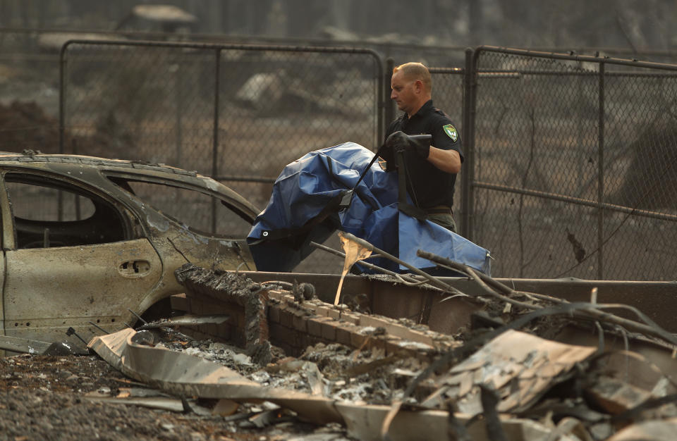 Sgt. Nathan Lyberger, of the Yuba County Sheriff's Department, carries a bag with human remains found at a burned out home at the Camp Fire, Sunday, Nov. 11, 2018, in Paradise, Calif. (AP Photo/John Locher)