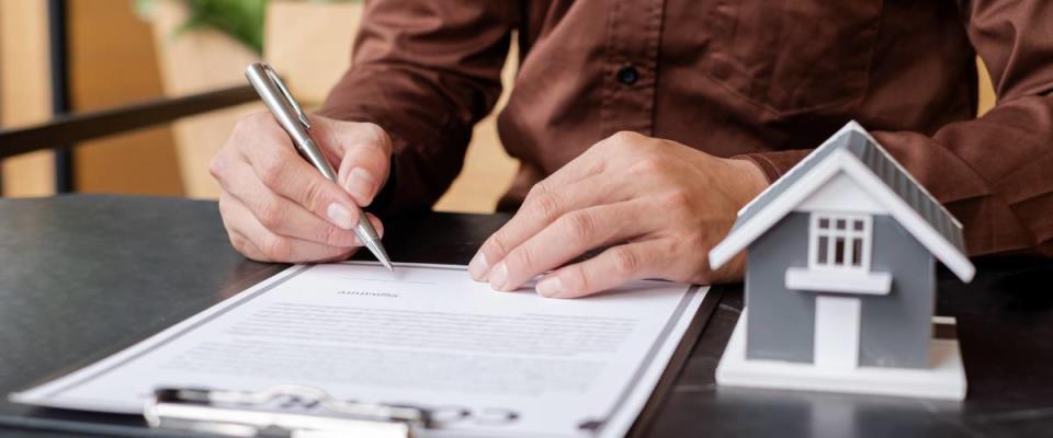 Close up of man signing contract for homeowners insurance.