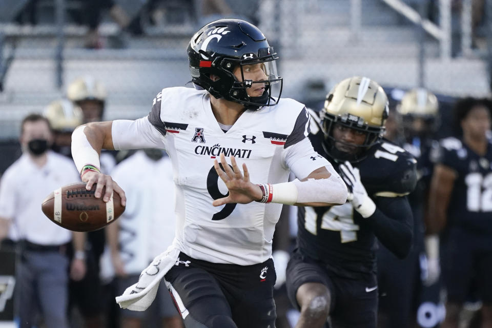 Cincinnati quarterback Desmond Ridder looks for a receiver as Central Florida defensive back Corey Thornton (14) pursues during the first half of an NCAA college football game, Saturday, Nov. 21, 2020, in Orlando, Fla. (AP Photo/John Raoux)