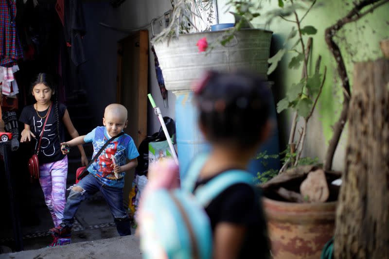 Hermes Soto plays as he walks followed by his sister, Africa Soto, at their house in Mexico City