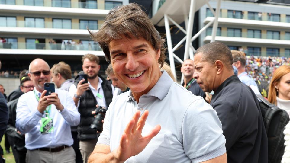 NORTHAMPTON, ENGLAND - JULY 03: Tom Cruise smiles on the grid before the F1 Grand Prix of Great Britain at Silverstone on July 03, 2022 in Northampton, England. (Photo by Bryn Lennon - Formula 1/Formula 1 via Getty Images)