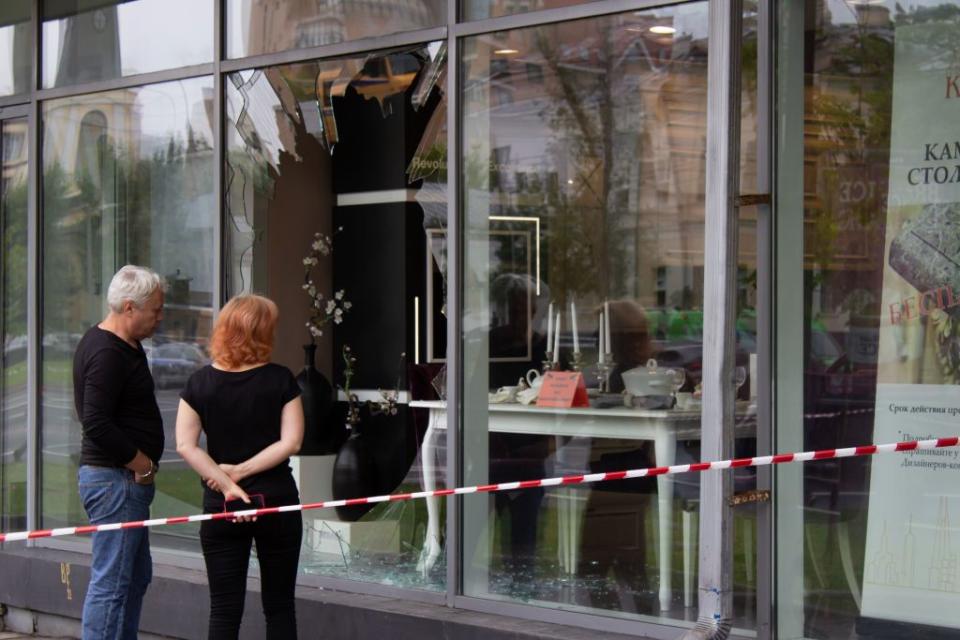 people observe the damage inflicted on a jewelry store by a