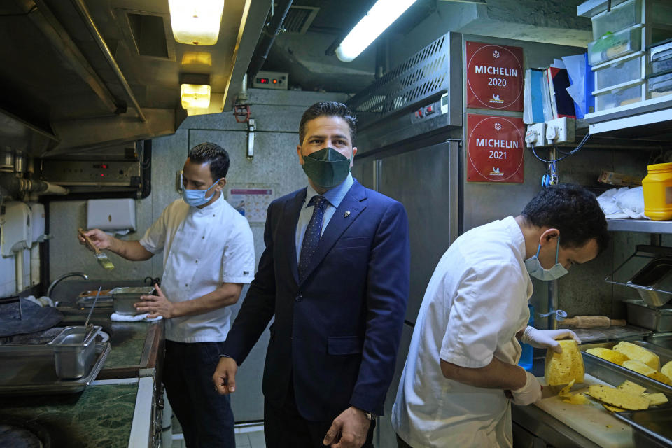 Sandeep Arora, center, from Punjab, India, a restaurant manager at Black Sheep's New Punjab Club, prepares food at its kitchen in Hong Kong on Nov. 26, 2021. The bustling, cosmopolitan business hub of Hong Kong may be losing its shine among foreign companies and expatriates with its stringent anti-pandemic rules requiring up to 21 days of quarantine for new arrivals. (AP Photo/Kin Cheung)