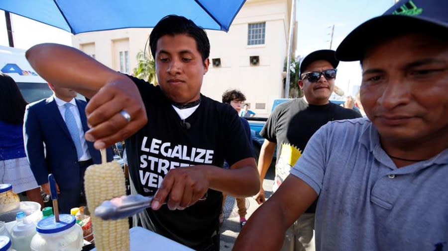 Benjamin Ramirez, left, with his father, Alex Ramirez, right, serving food from their cart during a rally in Hollywood. (Credit: Francine Orr / Los Angeles Times)