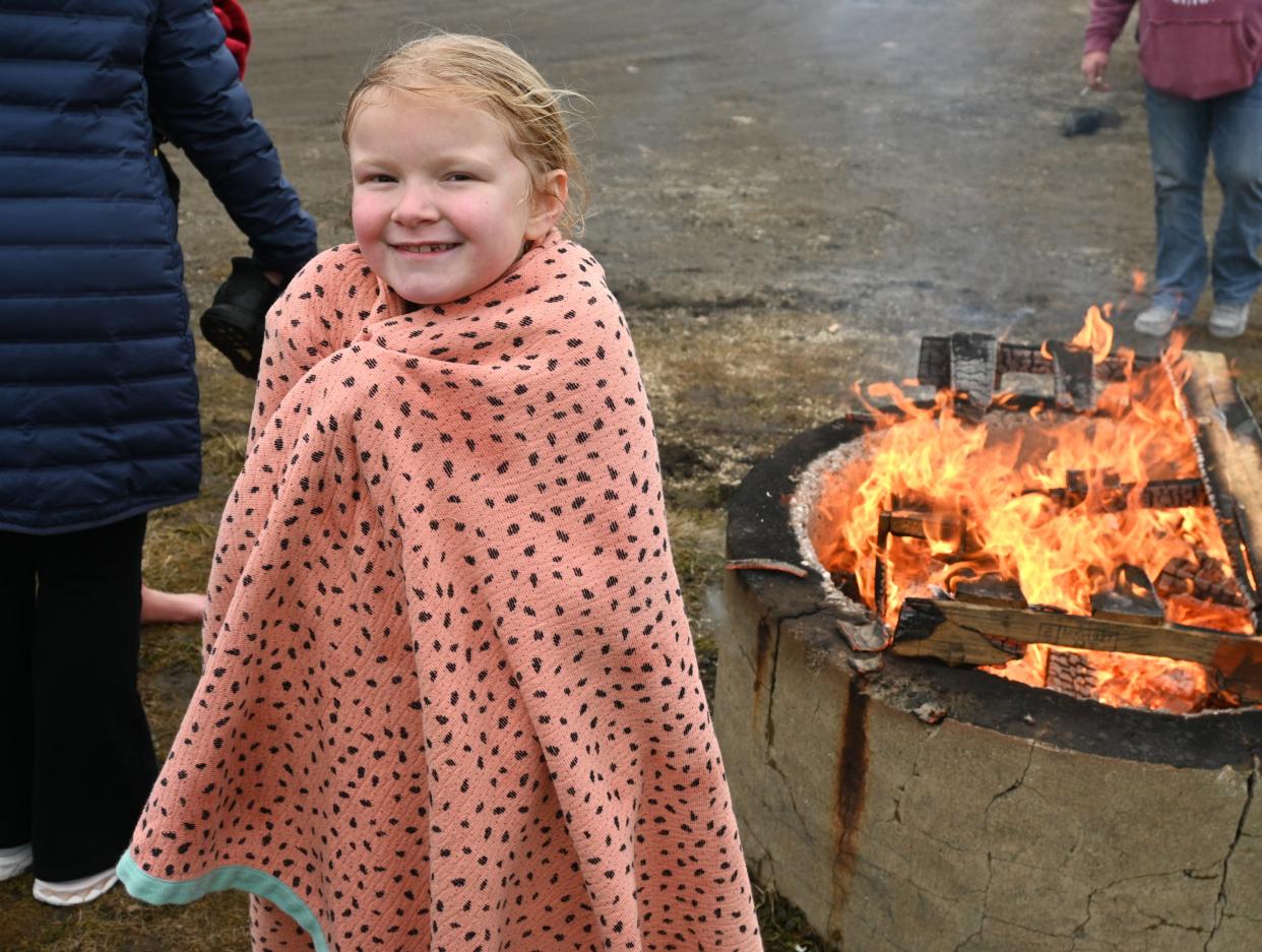 Kennedy Lah warms up by the fire after the Polar Plunge into Marble Lake on Saturday.