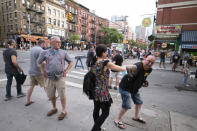Steve Grillo, right, bumps elbows with a friend in the Hell's Kitchen neighborhood of New York, Friday, May 29, 2020, during the coronavirus pandemic. Grillo lives on the blocked-off street and is a walking advertisement touting his West Side community. (AP Photo/Mark Lennihan)
