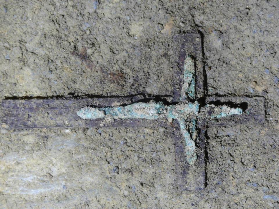 A wooden cross with a copper crucifix that was found in a burial.