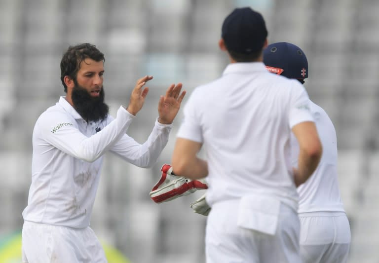 England's Moeen Ali (left) celebrates with teammates after taking the wicket of Bangladesh's Mominul Haque during their first day of the second Test match in Dhaka on October 28, 2016