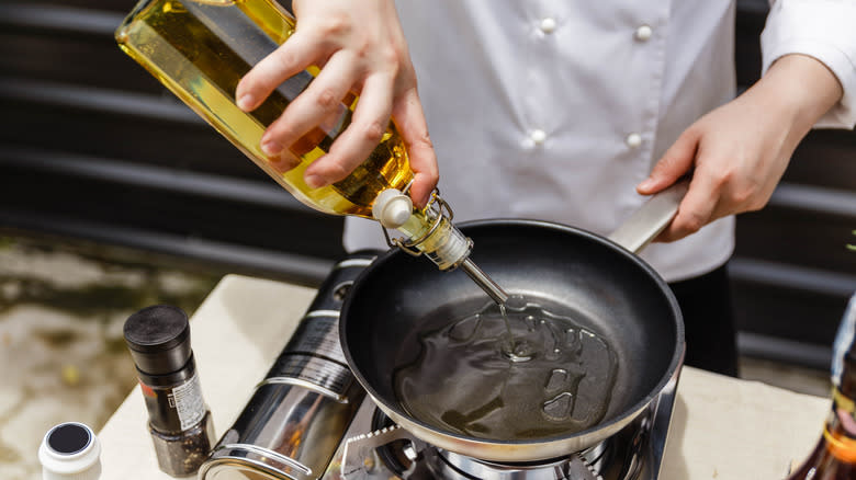 Pouring oil from bottle into skillet