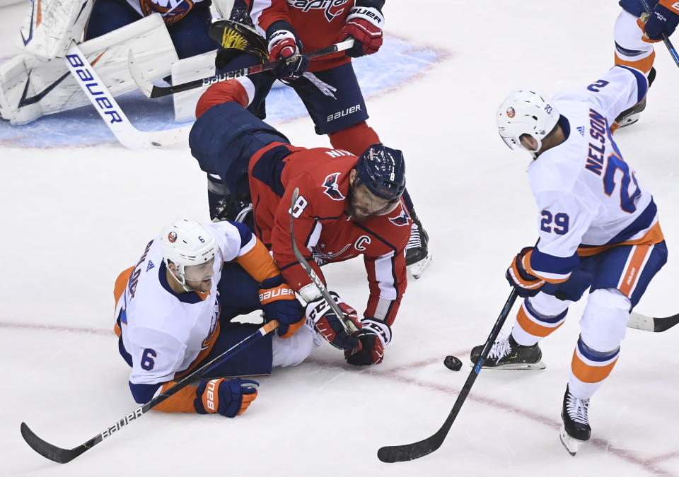 Washington Capitals left wing Alex Ovechkin (8) dives for the loose puck between New York Islanders defenseman Ryan Pulock (6) and center Brock Nelson (29) during the third period of an NHL Eastern Conference Stanley Cup hockey playoff game in Toronto, Friday, Aug. 14, 2020. (Nathan Denette/The Canadian Press via AP)