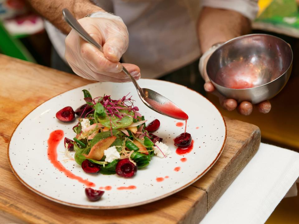 chef adding sauce garnish to dish