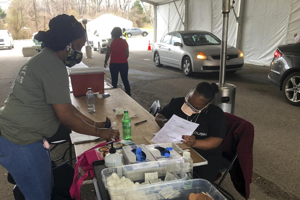 Workers organize paperwork and medical supplies as people wait in their cars to get a COVID-19 vaccination on Friday, March 12, 2021, in Memphis, Tenn. As millions continue to wait their turn for the COVID-19 vaccine, small but steady amounts of the precious doses have gone to waste across the country. It's a heartbreaking reality that experts acknowledged was always likely to occur. (AP Photo/Adrian Sainz)