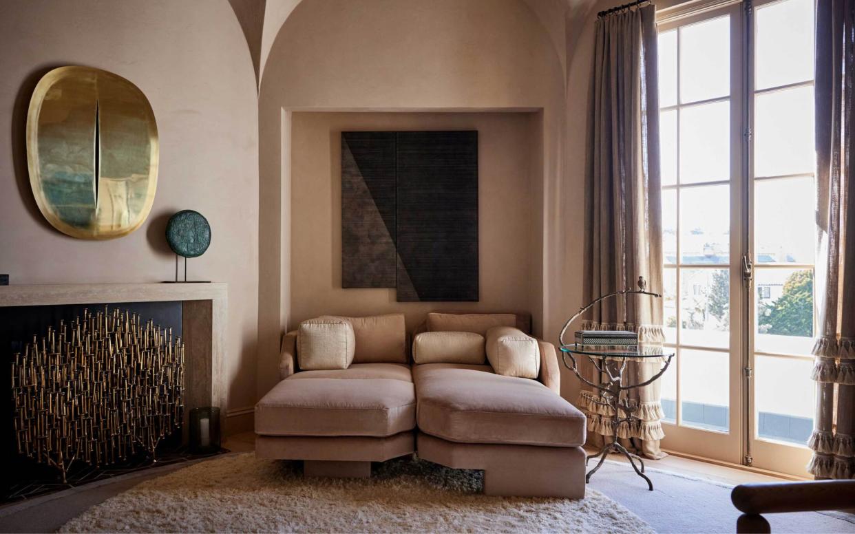  Terracotta walls living room with  ceiling arches, pink sofa and large artworks. 