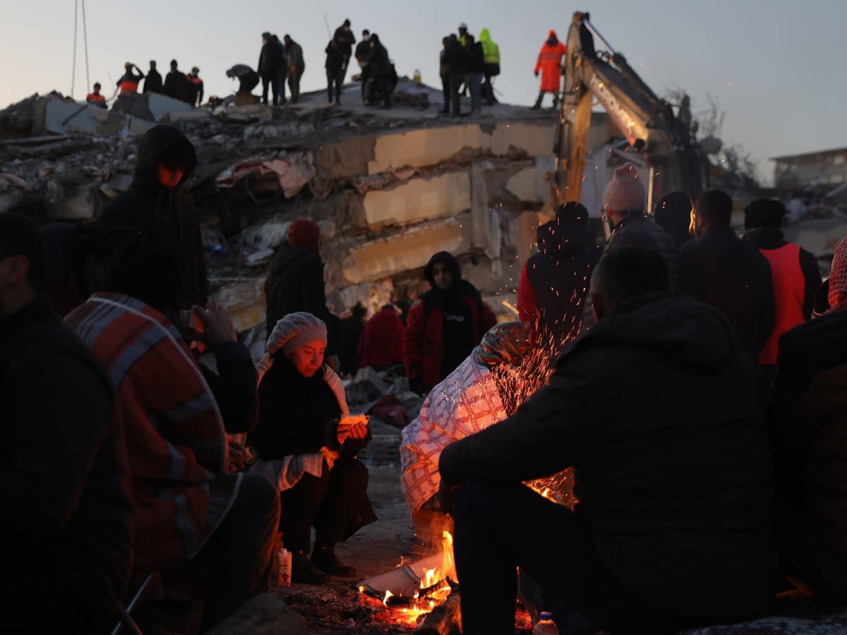People are keeping warm with bonfires amid the rubble (EPA)