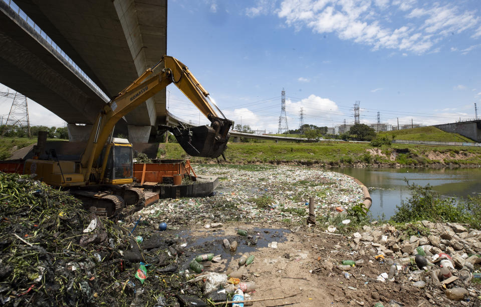 Una excavadora retira restos y basura de la orilla del río Pinheiros, en Sao Paulo, Brasil, el 22 de octubre de 2020. Tras años afectado por vertidos de aguas residuales y basura, el gobierno estatal de Sao Paulo está intentando de nuevo limpiar el río Pinheiros, considerado uno de los más contaminados del país. (AP Foto/Andre Penner)