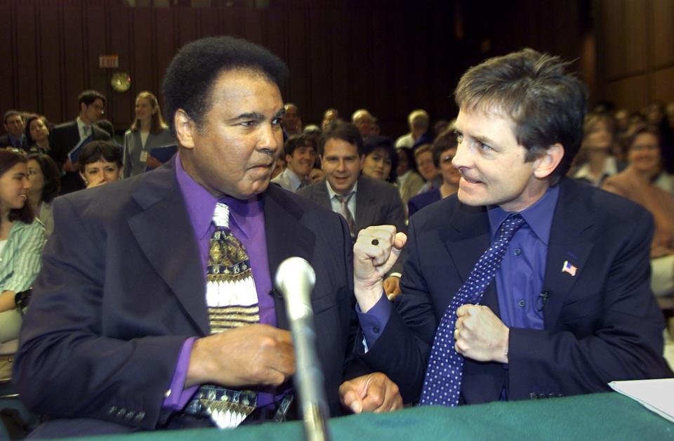 Muhammad Ali (left) and actor Michael J. Fox fist-bump as they testify before Congress