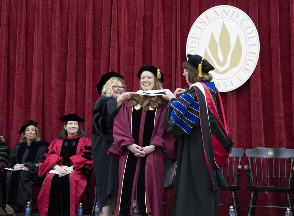  Rhode Island College Provost/Vice President of Academic Affairs Carolynn Masters, standing left, and Leslie Schuster, professor in the Department of History, standing right, recognize Vanessa E. Volz in a hooding ceremony at the Advanced Degree Ceremony on May 9, 2024, in the college’s Murray Center. Volz delivered the commencement address and received an honorary doctorate. Seated left to right are Dean of the School of Business Marianne Raimondo and Dean of the Faculty of Arts & Sciences Quenby Hughes. (Gene St. Pierre/Rhode Island College)