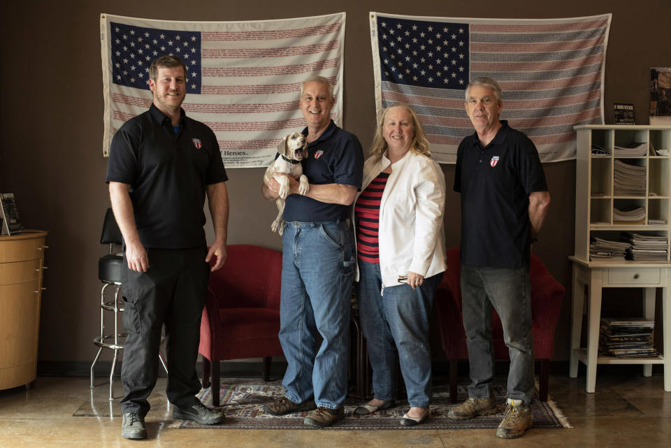 FILE - In this April 25, 2018, file photo, the owners and employees of Honor Defense, a gunmaker in Gainesville, Ga., pose in the company's lobby. Standing, left to right, are Pete Ramey, who works on the assembly line, Gary Ramey, the company's owner, his wife and company business manager, Pam Ramey, and Richard Moore, who works on the assembly line. Gary Ramey says that this year's SHOT Show, officially starting Tuesday, Jan. 21, 2020, will be especially critical to see products and meet suppliers for the parts he uses to make his line of handguns. (AP Photo/Lisa Marie Pane, File)