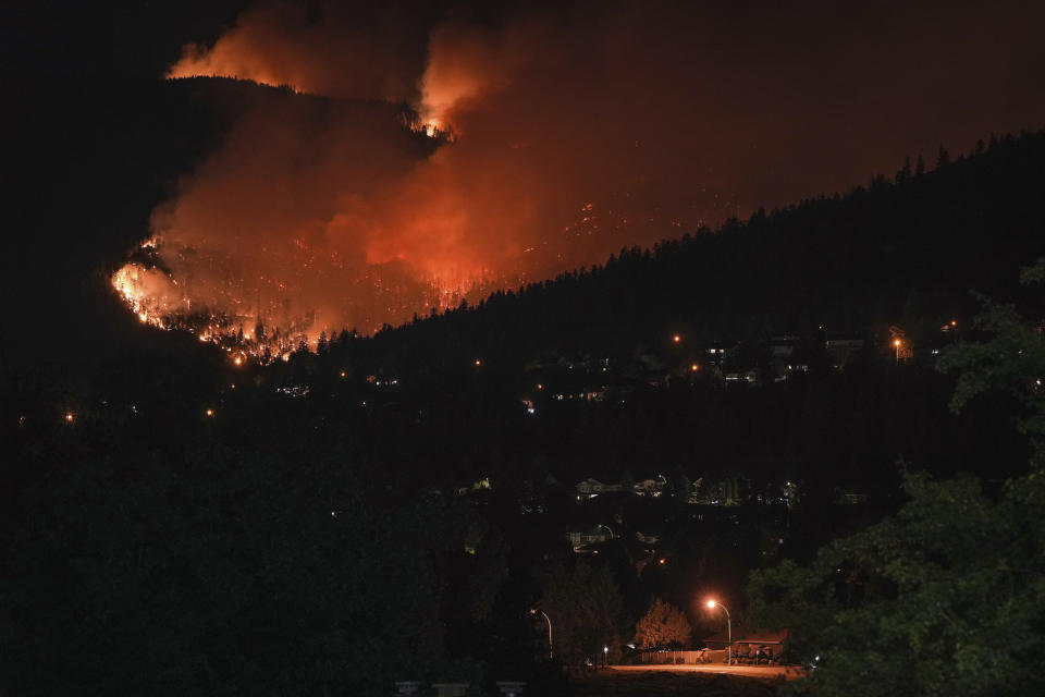 The McDougall Creek wildfire burns on the mountainside above a lakefront home in West Kelowna, B.C., on Friday, August 18, 2023. (Darryl Dyck/The Canadian Press via AP)