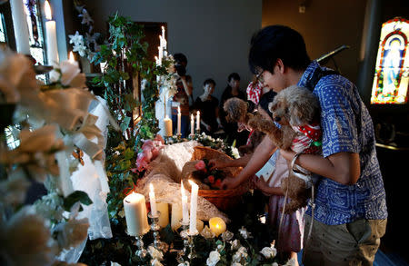 A family carrying their pet dogs places flowers on an altar for a pet dog during a demonstration of pet funeral services at the Pet Rainbow Festa, a pet funeral expo targeting an aging pet population, in Tokyo, Japan September 18, 2017. REUTERS/Kim Kyung-Hoon