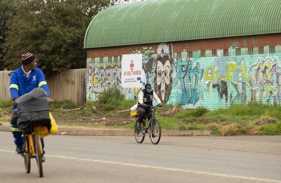 A man wearing face masks to protect against coronavirus, cycles on the street in Vosloorus, east of Johannesburg, South Africa, Thursday, April 2, 2020. South Africa went into a nationwide lockdown for 21 days in an effort to mitigate the spread to the coronavirus. The new coronavirus causes mild or moderate symptoms for most people, but for some, especially older adults and people with existing health problems, it can cause more severe illness or death. (AP Photo/Themba Hadebe)