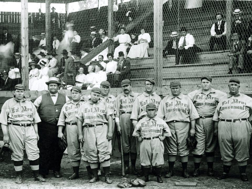 The baseball team representing the Fat Mans Baseball Association poses in their home ballpark circa 1910